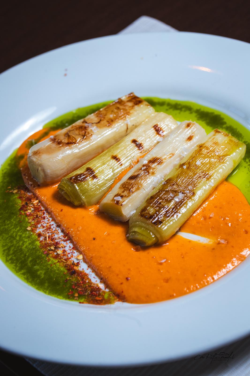 Puerros confitados con cama de salsa romesco